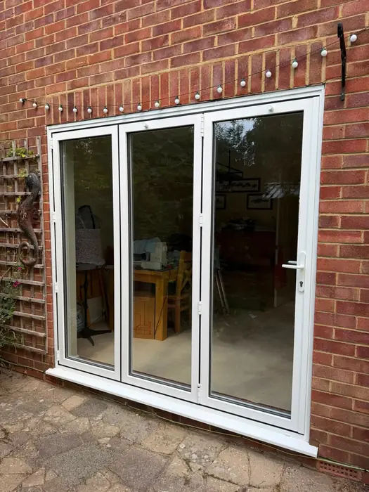 White uPVC bi-fold doors opening onto a garden, fitted by Team Frames