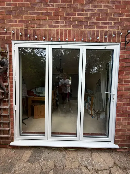 White uPVC bi-fold doors opening onto a garden, fitted by Team Frames
